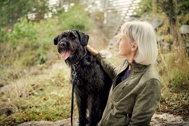 Frauchen und Hund sitzen nebeneinander im Wald.
