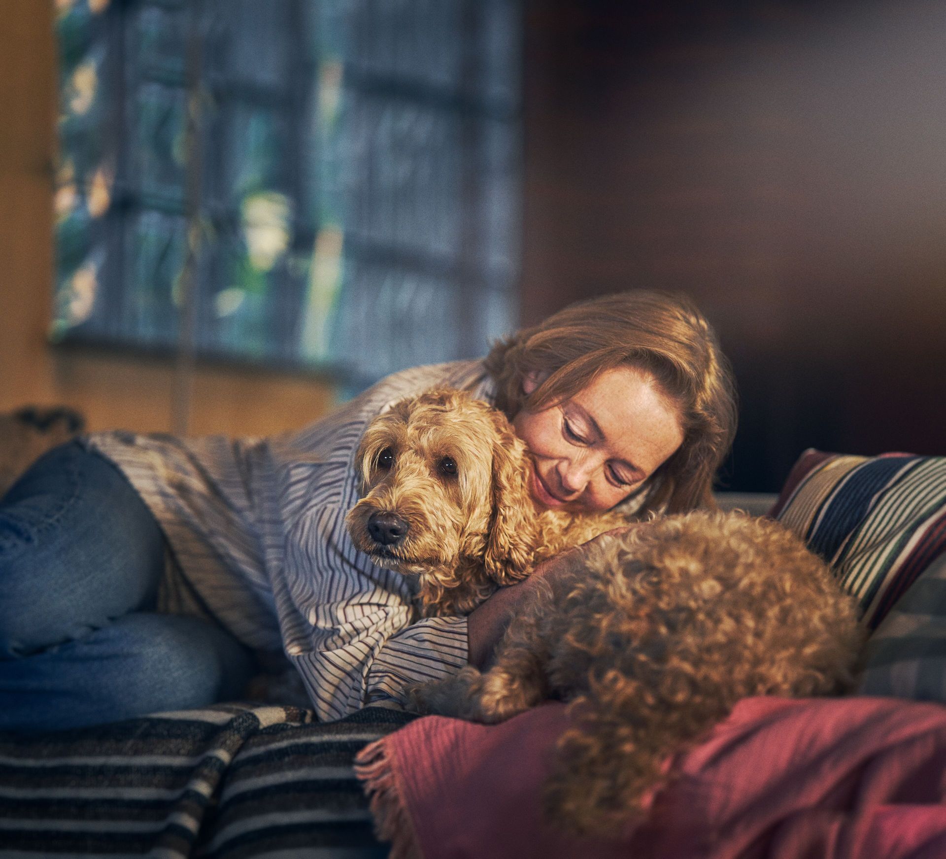 Frau umarmt ihren Hund auf dem Sofa.