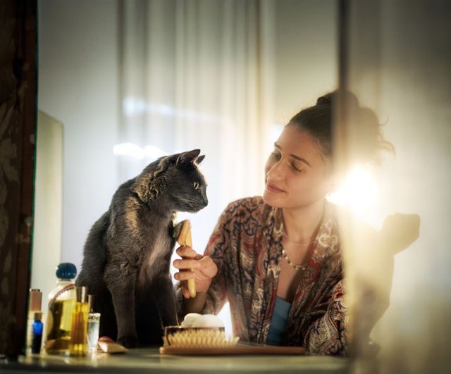 Katze sitzt neben Frau auf einem Tisch