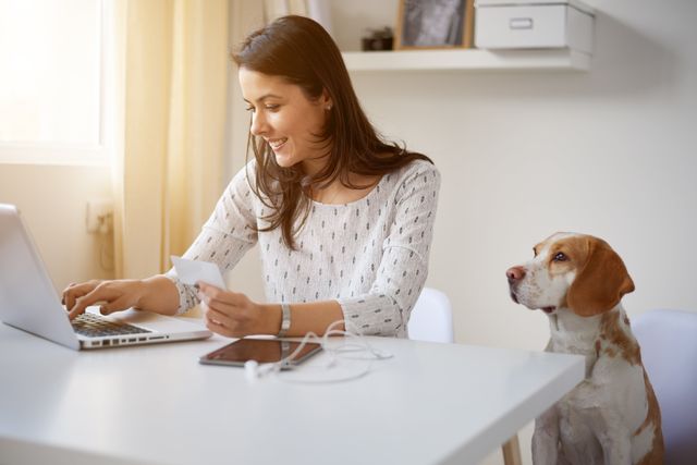 Frau mit Computer sitzt mit einem Hund daneben