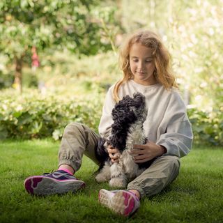 Mädchen und Hund sitzen im Garten