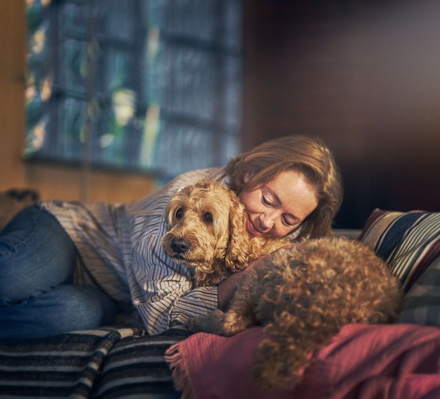 Eine Frau kuschelt mit ihrem Hund auf dem Sofa.