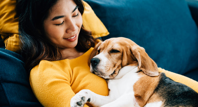 Frau kuschelt mit ihrem Beagle.