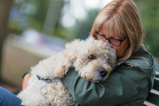 Frau kuschelt mit Hund.